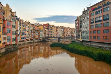 Yahudi mahallesindeki renkli sarı ve turuncu evler Girona, Katalonya, İspanya 'daki su nehrine yansıyor.