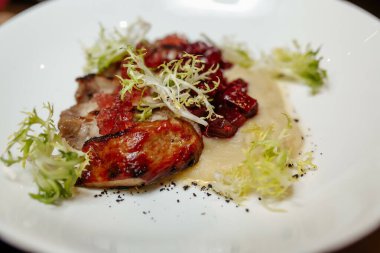 Ahşap bir masada yeşil salatalı ızgara domuz bifteği.