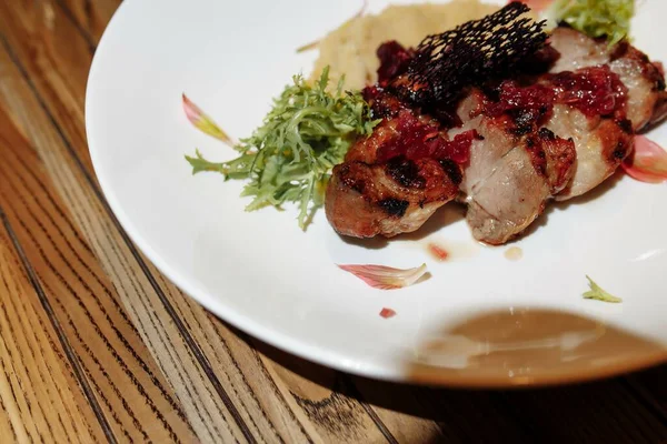 Ahşap bir masada yeşil salatalı ızgara domuz bifteği.