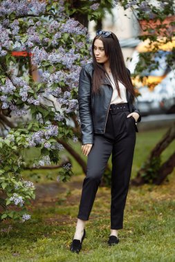 Gülen ve gülümseyen güzel, mutlu, uzun saçlı model kız yaz leylak bahçesinde kameraya poz veren çiçekler. Saç konseptiyle oynamak.