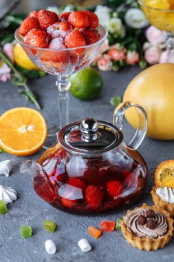 Meyve ahududu çayı ve nane arkaplanda meyve ve süslemelerle dolu cam çaydanlık..