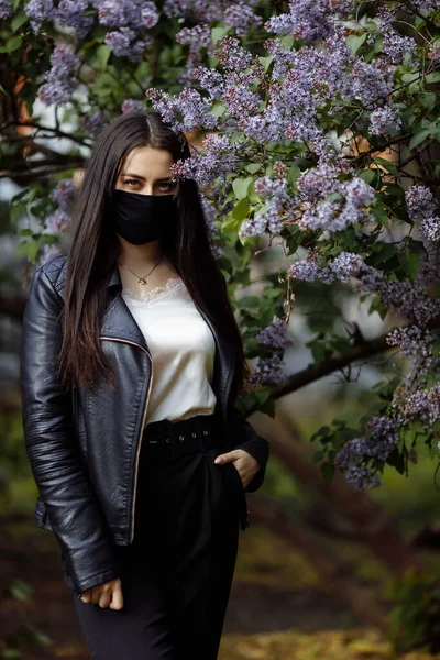 Menina Uma Máscara Médica Contexto Lilases Florescentes Máscara Preta Protecção — Fotografia de Stock