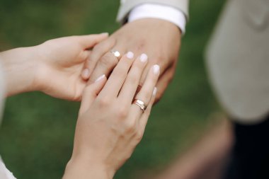 Yeni evlilerin elleri ve alyansları ve düğün buketi. Alyansları ve düğün buketi olan yeni evliler..