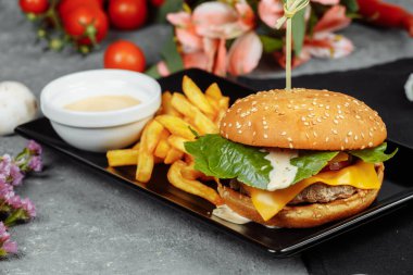 Pirzola, peynir ve domatesli hamburger. Patates kızartması ve hamburger sosuyla..