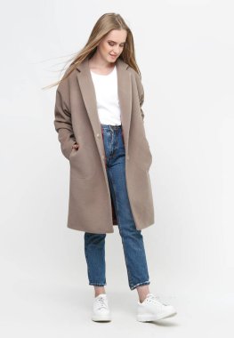 Beyaz arka planda kahverengi uzun bir ceketle poz veren güzel bir manken. Stüdyo. Kıyafet reklamcılığı konsepti.