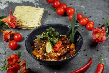 Erişteler, dana eti ve sebzeler gri masada..