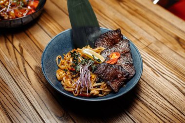 Erişteler, dana eti ve sebzeler gri masada..