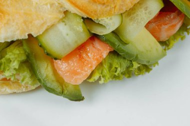 Kırmızı balıklı kruvasan sandviçi, avokado, taze sebzeler ve siyah taş zemin üzerinde roka. Sağlıklı gıda konsepti.