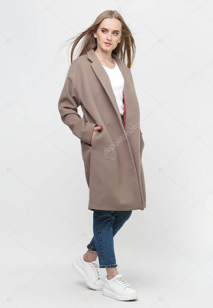 beautiful model posing in a brown long coat on a white background. studio shot. Clothing advertising concept.