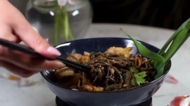 Japon yemeği: karıştırılmış soba eriştesi ve siyah kasede sebze. Lezzetli, besleyici Asya yemekleri.