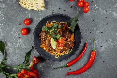 Erişteler, dana eti ve sebzeler gri masada..