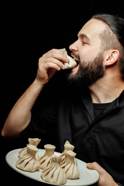 El barbudo está comiendo khinkali emocionalmente. El plato nacional georgiano khinkali. Concepto de foto publicitaria de Khinkali — Foto de Stock