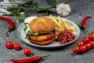 Patates kızartmalı tavuk burger ve eski beton arka planda salata..