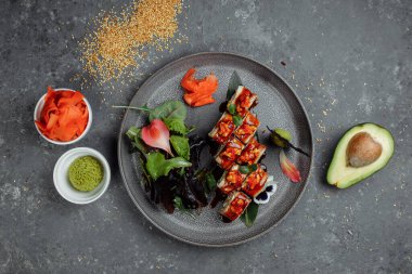 Geleneksel Japon yemekleri. Suşi gri arka planda yılan balığıyla yuvarlanır. bir yazıt için yer