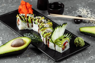 Yılan balığı, avokado, salatalık ve zencefilli yeşil ejderha suşisi yanında kızarmış tempura karidesi. Geleneksel Asya pirinç suşisi sağlıklı deniz ürünleri.
