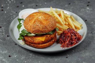 Patates kızartmalı tavuk burger ve eski beton arka planda salata..