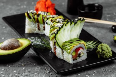 Yılan balığı, avokado, salatalık ve zencefilli yeşil ejderha suşisi yanında kızarmış tempura karidesi. Geleneksel Asya pirinç suşisi sağlıklı deniz ürünleri.