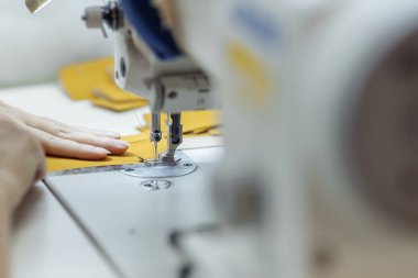 Dikiş makinesi kumaş karalıyor. Fabrikada terzilik..