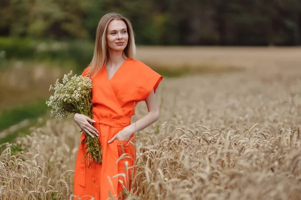 Une belle jeune femme marche dans un champ de blé — Photo