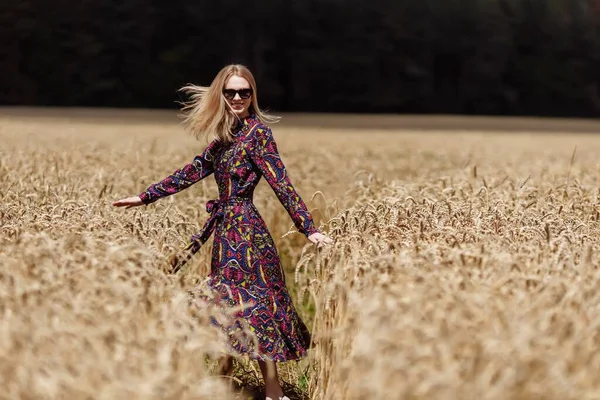 Eine schöne junge Frau geht in einem Weizenfeld — Stockfoto