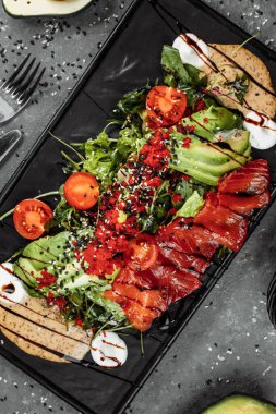 Somon salatası Gravlax. Füme somon salatası, karışık yeşillikler, kiraz domatesleri, avokado, siyah zeytin, havuç, lahana, salatalık ve limon. Lezzetli sağlıklı yemek.