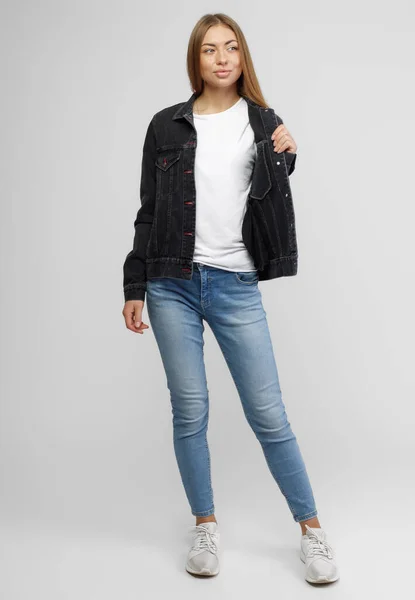 Meisje in een denim zwart jasje en blauwe denim broek op een witte achtergrond — Stockfoto