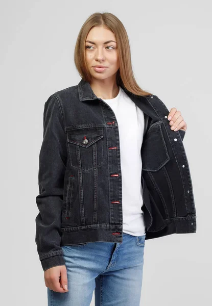Menina em uma jaqueta preta jeans e calças jeans azuis em um fundo branco — Fotografia de Stock