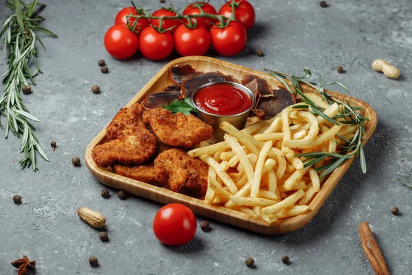 Plato con bocadillos. nuggets de pollo empanados, papas fritas y jamón Imagen De Stock