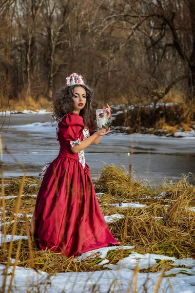 Mooi meisje in vintage rode jurk met een roos — Stockfoto