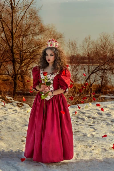 Mooi meisje in vintage rode jurk met een roos — Stockfoto
