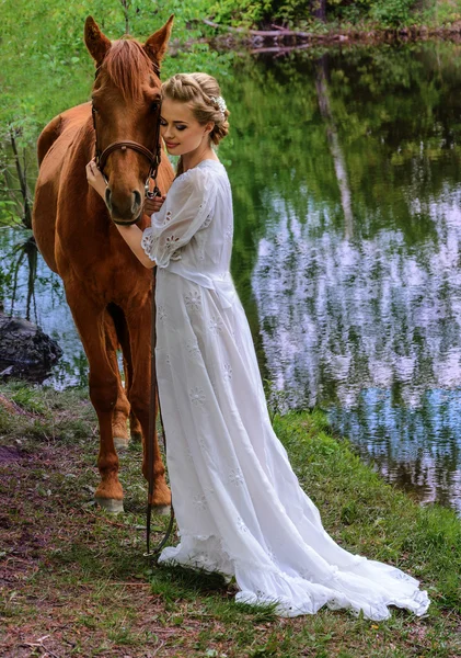 Woman standing with horse near lake and touching horse face with her forehead — Stock Photo, Image