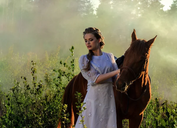 Kobieta w białej sukni z konia w zielonej okolicy — Zdjęcie stockowe