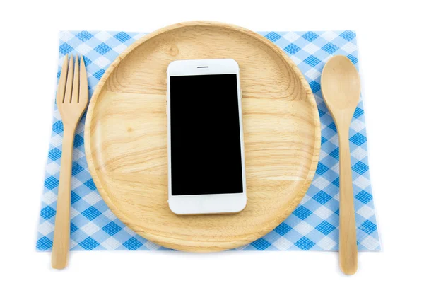 Вид сверху смартфон на деревянной тарелке с ложкой и вилкой на белом фоне, концепция — стоковое фото