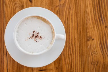 Üst sanat Latte Kahve ahşap masa üzerinde beyaz bir fincan.