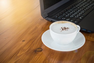 Ahşap masa ile bilgisayar dizüstü bilgisayar arka plan beyaz bir bardakta sanat Latte Kahve