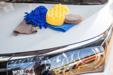Yellow, green sponges and blue mitts for washing and microfiber fabric with cleaner cloth on white car clipart