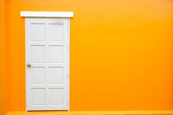 Белая дверь классический винтаж на фоне оранжевого цвета стены — стоковое фото