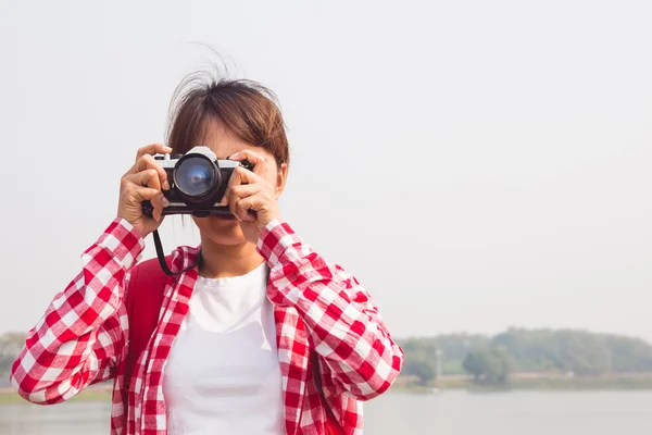 Gadis muda bepergian dengan ransel dan menangani kamera mengambil foto. konsep perjalanan — Stok Foto