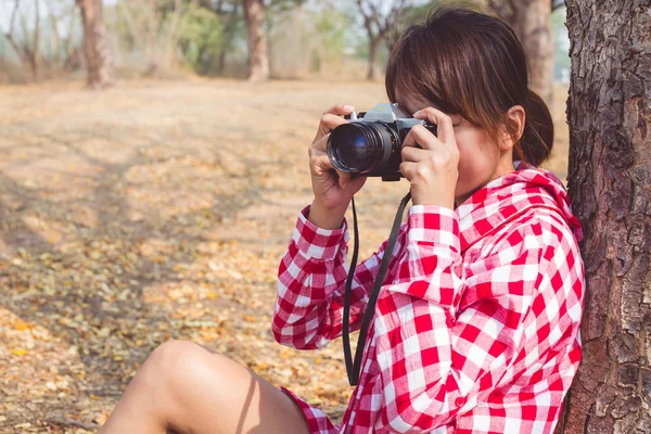 Turista joven sosteniendo la vieja cámara de fotos vintage tomar una foto al aire libre — Foto de Stock