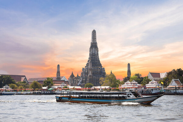 The Temple of Dawn, Wat Arun, on the Chao Phraya river with passenger ships or boat and a beautiful sky in twilight time at Bangkok, Thailand