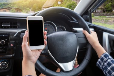 Japon geleneksel (Shirakawa-go) köyünün arka planında, dokunmatik ekranlı akıllı telefon ve direksiyon kullanan genç bir kadın sürücü.