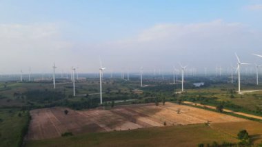 Tayland 'da arka plan olarak dağlarla ve gökyüzüyle çayırlarda elektrik üretmek için birçok rüzgar türbini.