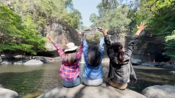 Freiheitsreisende Gruppe Von Frauen Sitzt Wasserfallfront Auf Stein Und Umarmen — Stockvideo
