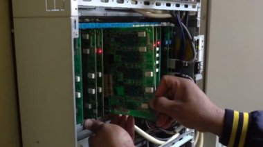 Teknisyen veya mühendis anakart, PBX, dijital sistem bağlantısını gösteren yanıp sönen ışıklarla telefon değiştirir
