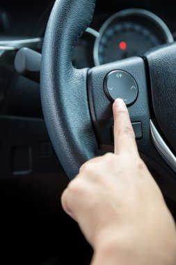 Bir kadın el ses kontrol düğmesi bir direksiyon simidi üzerinde iter..