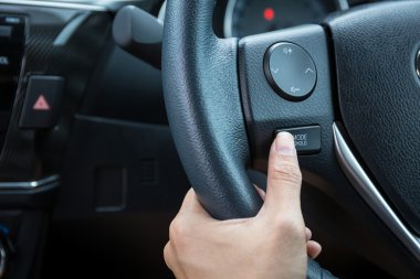 Bir kadın el modu tutun kontrol butonu bir direksiyon simidi üzerinde iter..