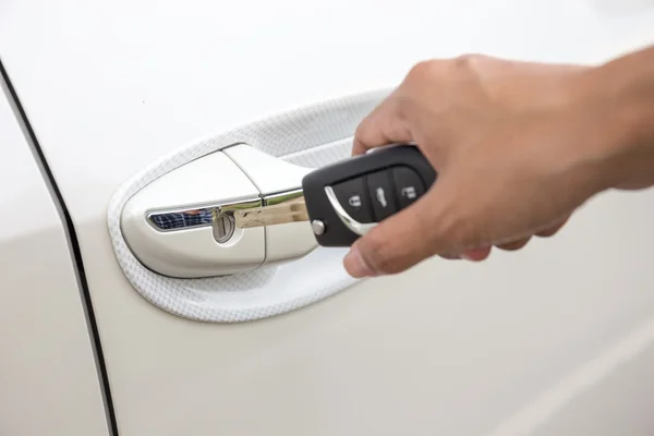 Крупный план женской руки, вставляющей ключ в дверной замок белой машины. (замочная скважина ) — стоковое фото