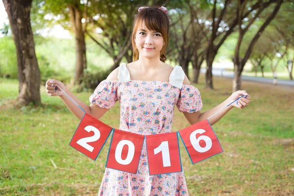 Sorriso della mano della donna carina che tiene il segno di carta 2016, felice anno nuovo — Foto Stock