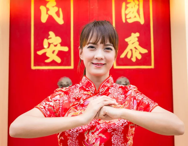 З китайським новим роком. Мила азіатка з жестом привітання ізольована на червоному підборідді традиційний фон (текст "Щасливий")) — стокове фото