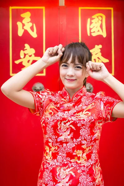 Frohes chinesisches neues Jahr. Nette asiatische Frau mit Geste der Gratulation isoliert auf rotem chinesischem Muster traditionellen Hintergrund (Text "Glück" 'Schutzschild') — Stockfoto
